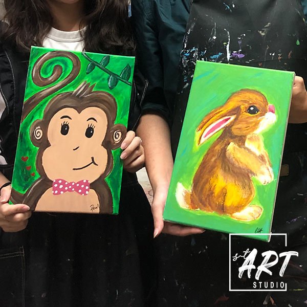 Child confidence class Singapore, student proudly showing completed paintings at stART Studio